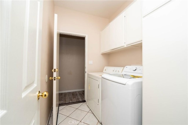 laundry area with separate washer and dryer, cabinets, and light tile patterned flooring