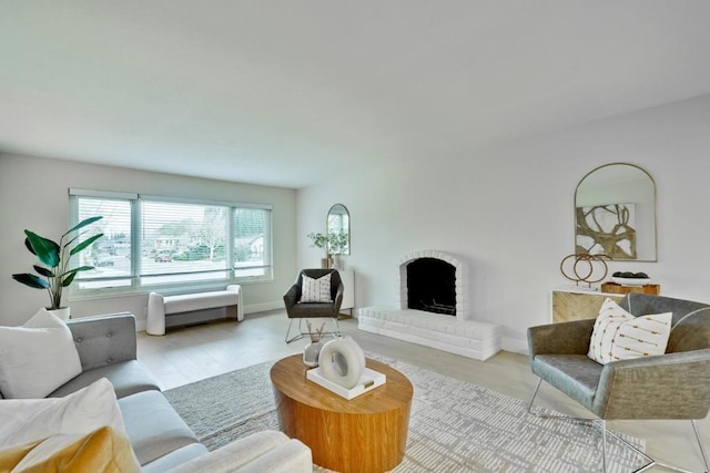 living room featuring a brick fireplace and light wood-type flooring