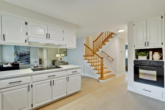 kitchen with white cabinetry, light wood-type flooring, and black appliances