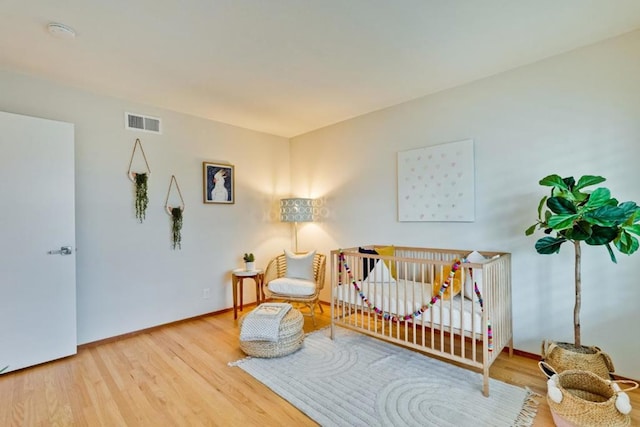 bedroom featuring hardwood / wood-style flooring and a crib