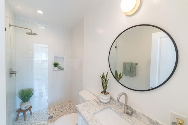 bathroom with vanity, toilet, and tiled shower