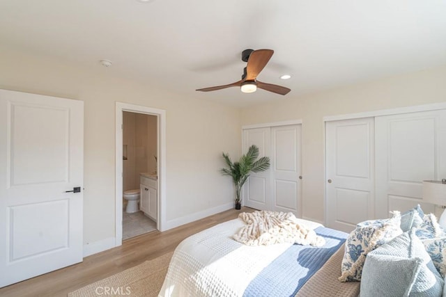 bedroom with ceiling fan, ensuite bathroom, multiple closets, and light wood-type flooring