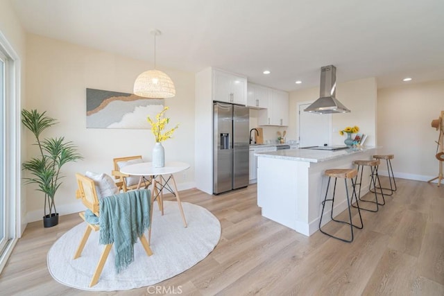 kitchen featuring hanging light fixtures, stainless steel refrigerator with ice dispenser, light stone countertops, white cabinets, and island exhaust hood