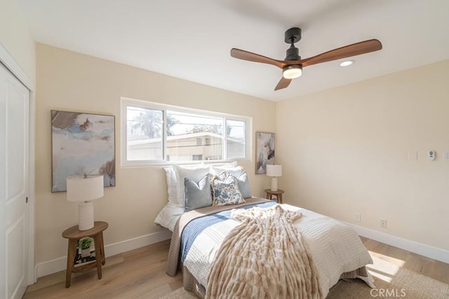 bedroom featuring light hardwood / wood-style flooring, ceiling fan, and a closet