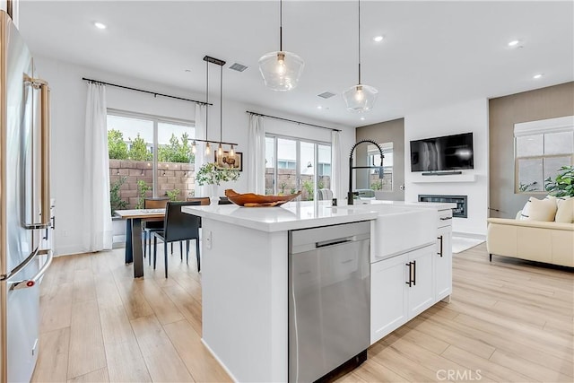 kitchen featuring white cabinetry, sink, hanging light fixtures, a kitchen island with sink, and stainless steel appliances