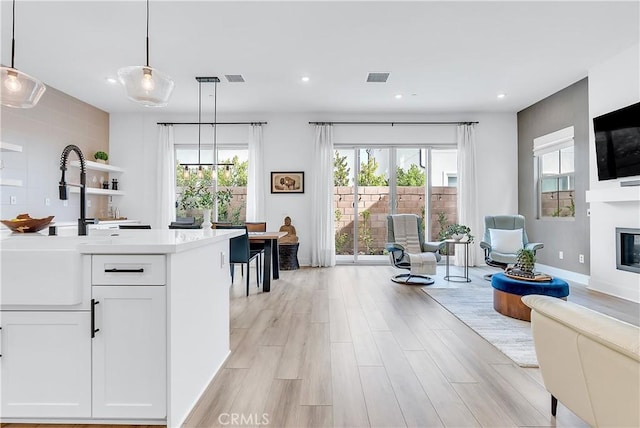 interior space featuring a healthy amount of sunlight, light hardwood / wood-style flooring, hanging light fixtures, and white cabinets