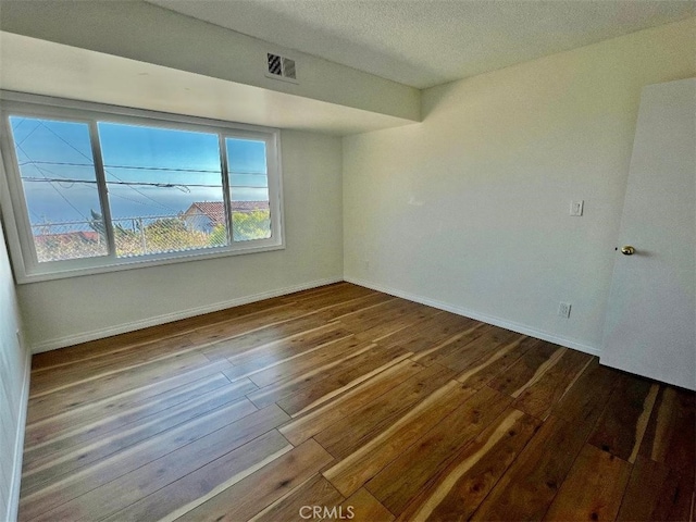 spare room featuring hardwood / wood-style floors and a textured ceiling