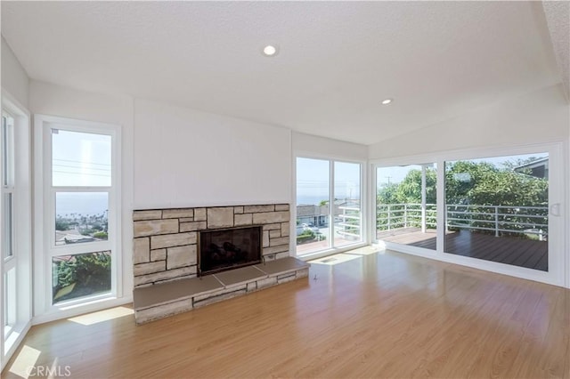 unfurnished living room with a fireplace, vaulted ceiling, and light wood-type flooring