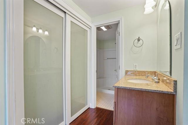 bathroom featuring wood-type flooring, vanity, and walk in shower