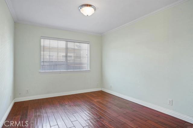 unfurnished room featuring dark wood-type flooring and ornamental molding