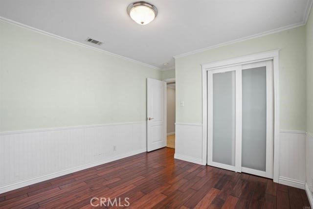 unfurnished bedroom featuring crown molding, dark hardwood / wood-style flooring, and a closet