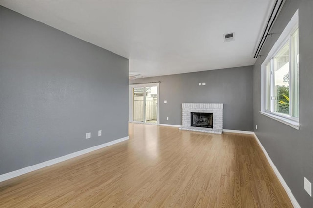 unfurnished living room with a brick fireplace and light wood-type flooring