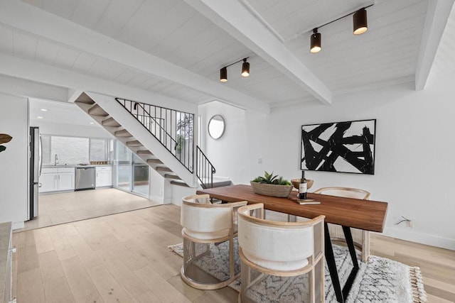 dining space featuring beam ceiling, sink, rail lighting, and light wood-type flooring