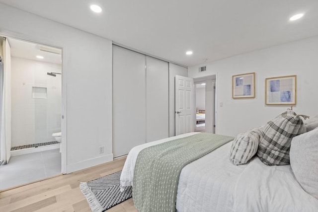 bedroom featuring connected bathroom, light wood-type flooring, and a closet