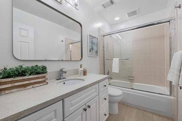 full bathroom with enclosed tub / shower combo, vanity, and toilet