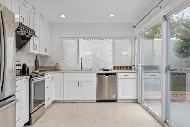 kitchen featuring white cabinetry, sink, stainless steel appliances, and exhaust hood