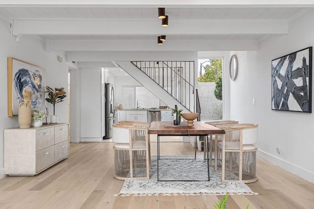 dining area featuring beamed ceiling and light wood-type flooring