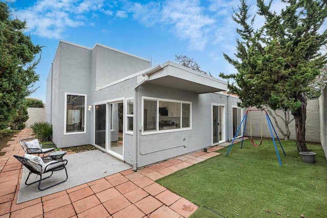 rear view of house featuring a playground, a yard, and a patio area