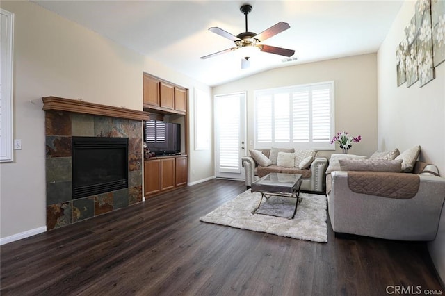 living room featuring vaulted ceiling, dark hardwood / wood-style floors, ceiling fan, and a fireplace