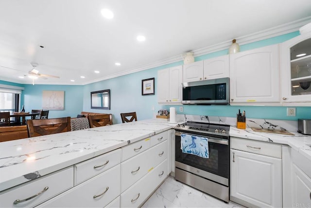 kitchen featuring appliances with stainless steel finishes, white cabinetry, a wealth of natural light, light stone countertops, and ornamental molding