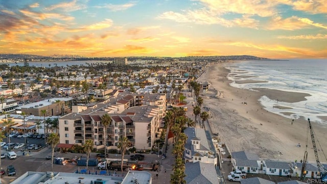 aerial view at dusk with a beach view and a water view