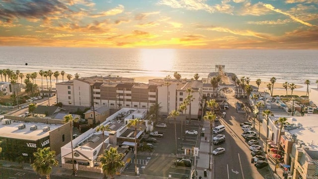 aerial view at dusk with a water view and a view of the beach