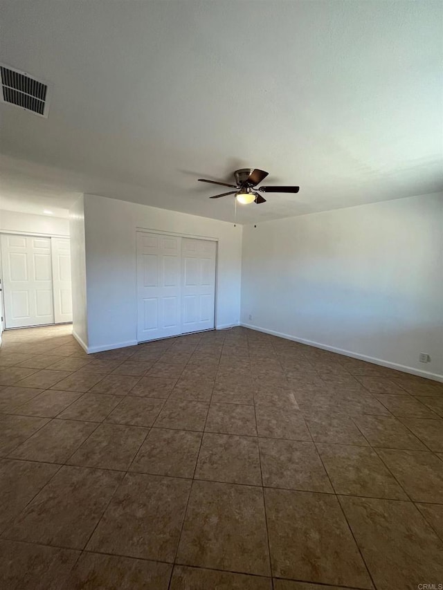 unfurnished bedroom with baseboards, visible vents, a ceiling fan, dark tile patterned flooring, and a closet