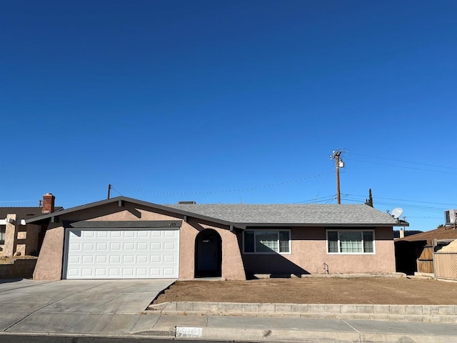 view of front of home with driveway, roof with shingles, an attached garage, and stucco siding