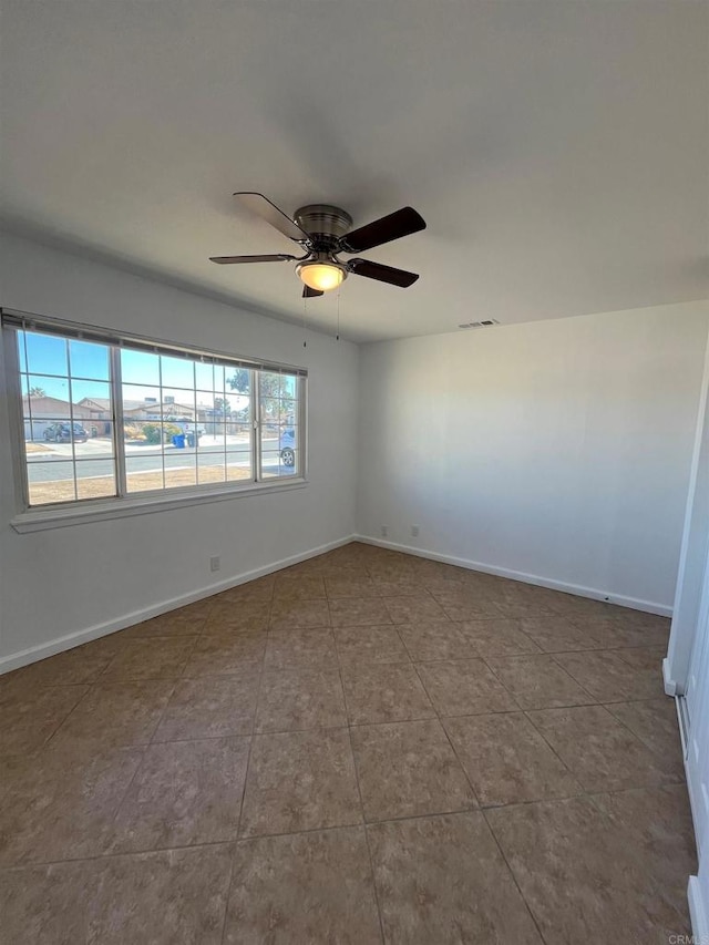 tiled empty room with a water view, ceiling fan, and baseboards