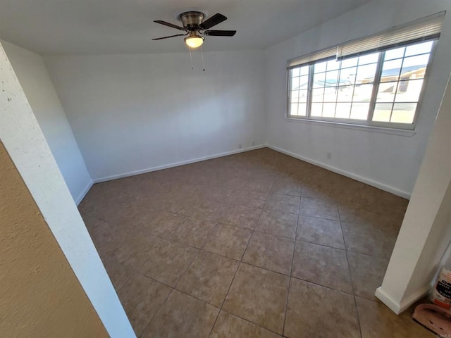 spare room featuring tile patterned flooring, ceiling fan, and baseboards