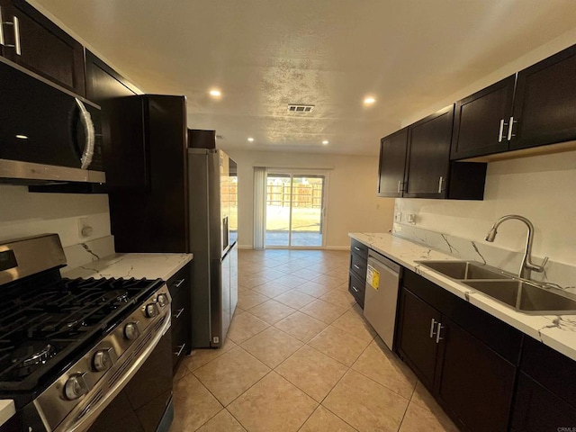 kitchen with light tile patterned floors, visible vents, appliances with stainless steel finishes, light stone countertops, and a sink