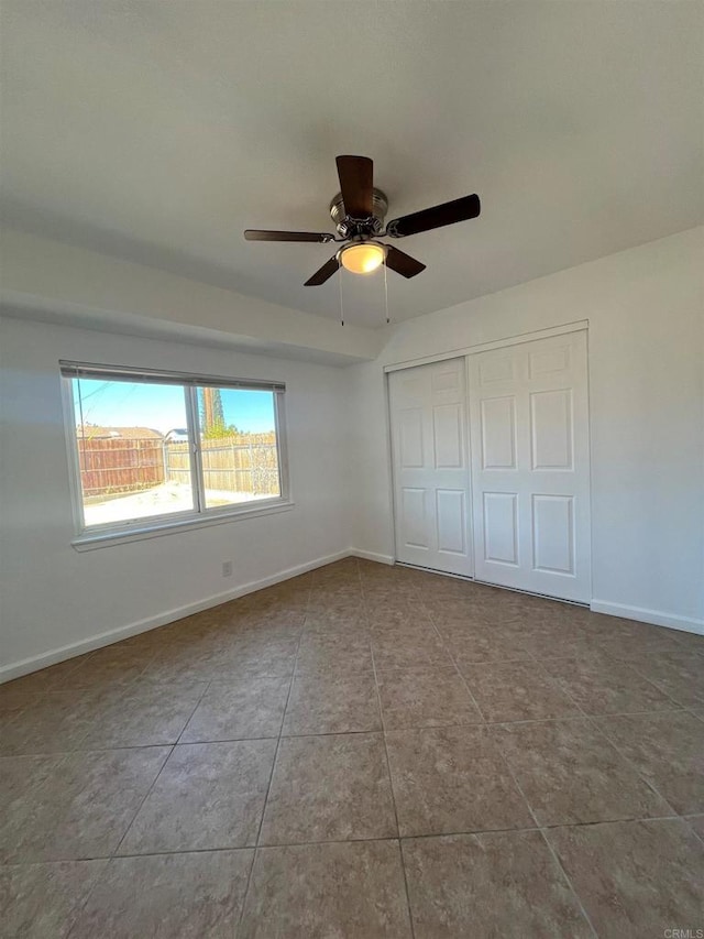 unfurnished bedroom featuring ceiling fan, baseboards, a closet, and light tile patterned flooring