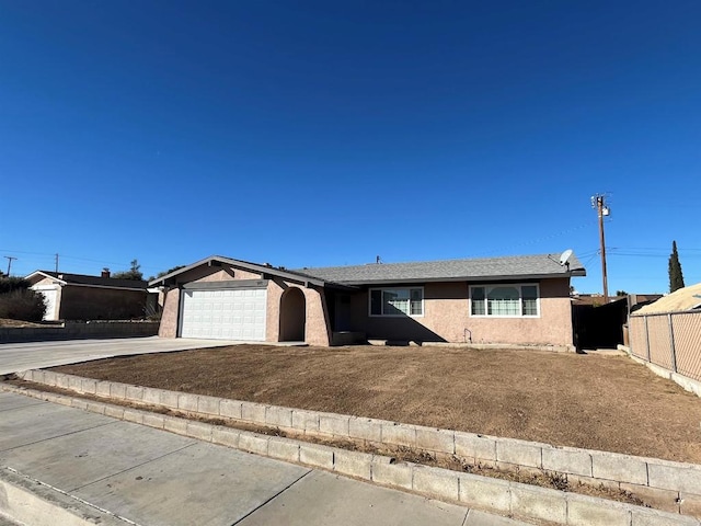 ranch-style home with a garage, concrete driveway, fence, and stucco siding