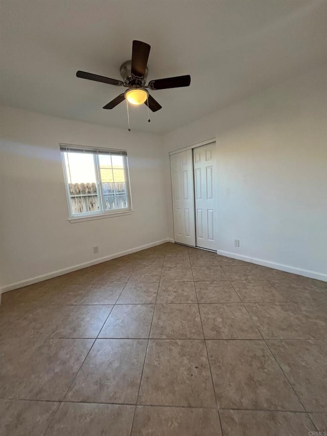 unfurnished bedroom featuring ceiling fan, baseboards, a closet, and light tile patterned flooring