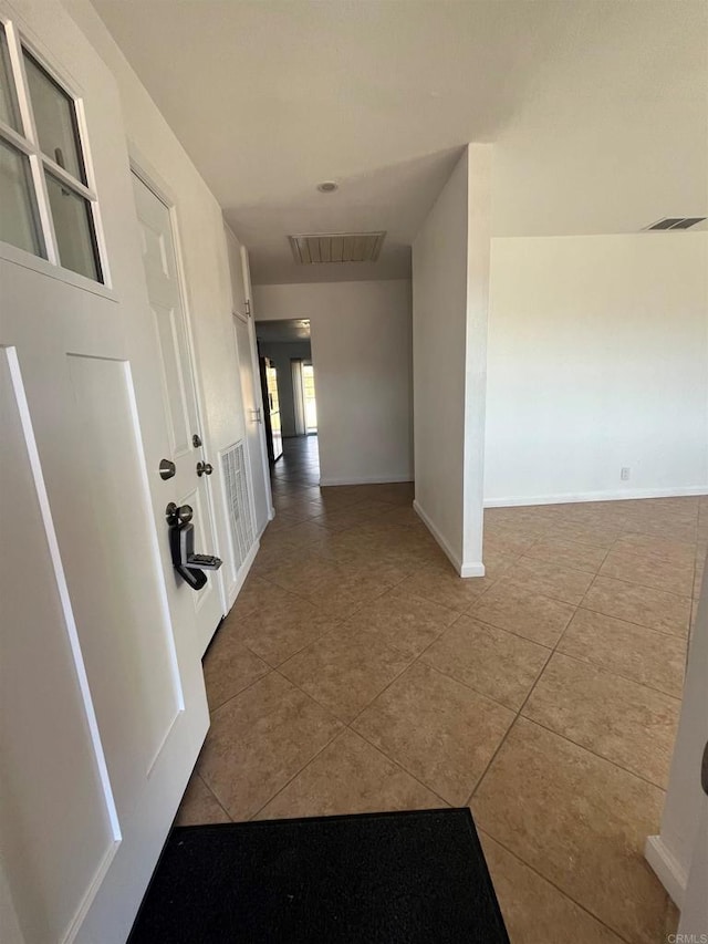 hallway featuring tile patterned flooring, visible vents, and baseboards