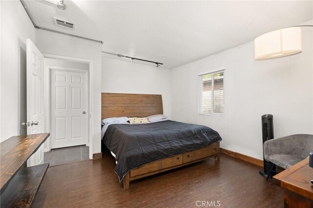 bedroom featuring dark hardwood / wood-style flooring and rail lighting