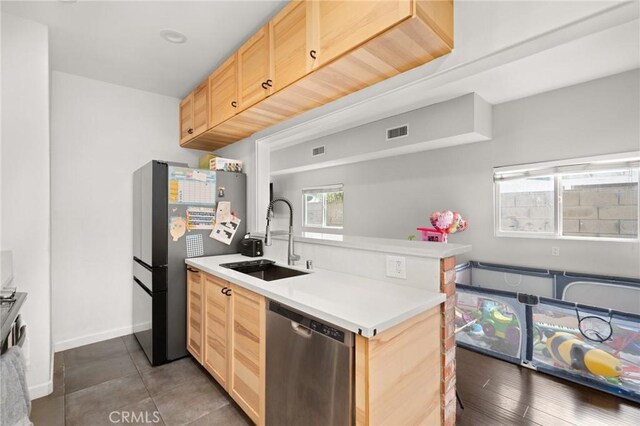 kitchen featuring stainless steel appliances, light brown cabinetry, and sink