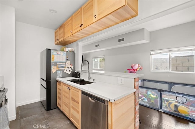 kitchen with visible vents, light brown cabinetry, a sink, stainless steel appliances, and a peninsula