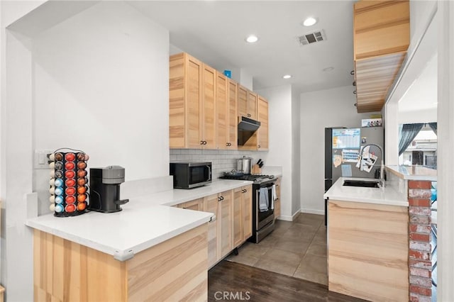 kitchen with a sink, tasteful backsplash, appliances with stainless steel finishes, and light brown cabinetry