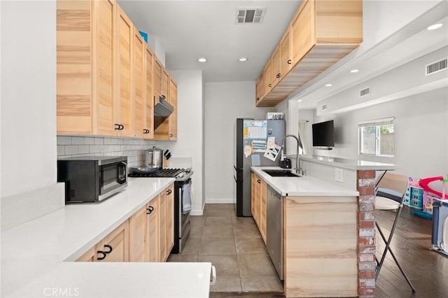 kitchen featuring light tile patterned flooring, appliances with stainless steel finishes, tasteful backsplash, a kitchen breakfast bar, and light brown cabinets