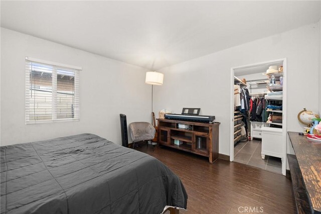 bedroom with a closet, a spacious closet, and dark hardwood / wood-style floors