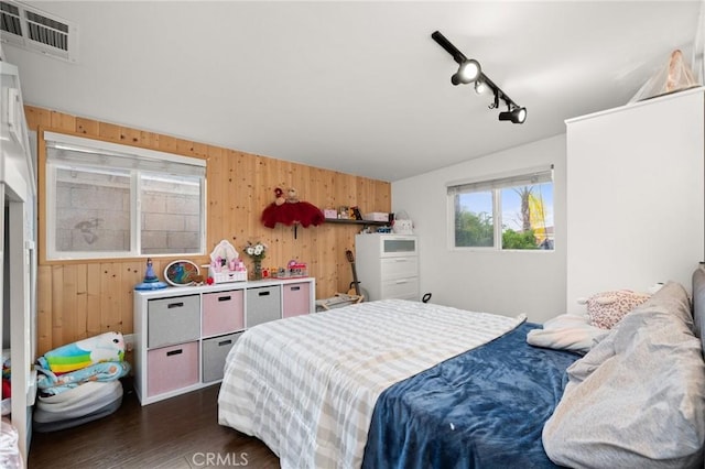 bedroom featuring dark hardwood / wood-style floors, track lighting, and wooden walls