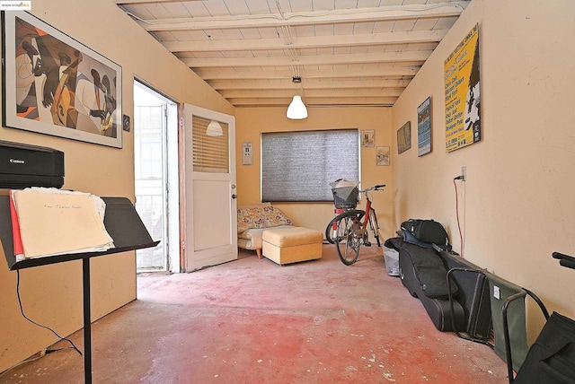 misc room with concrete flooring and lofted ceiling with beams