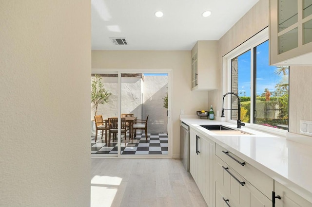 kitchen with sink, stainless steel dishwasher, and light wood-type flooring