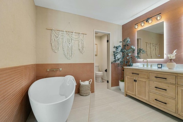 bathroom featuring tile walls, a bathtub, vanity, tile patterned floors, and toilet