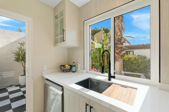 kitchen with dishwasher, sink, and white cabinets