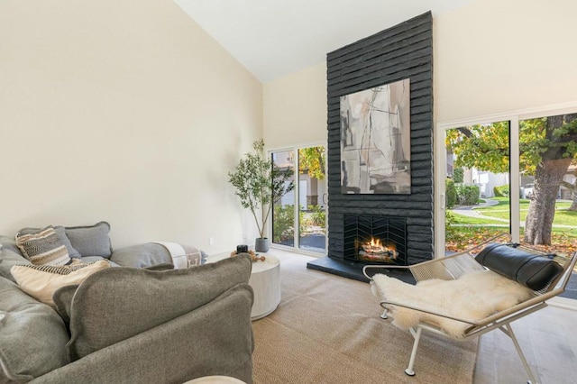 carpeted living room featuring a fireplace and high vaulted ceiling