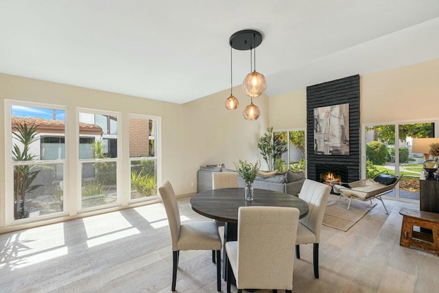 dining room with light hardwood / wood-style flooring and a large fireplace