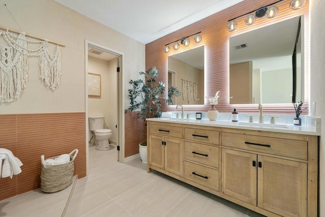 bathroom featuring vanity, tile walls, tile patterned floors, and toilet