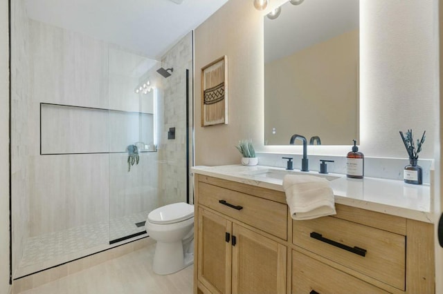 bathroom featuring vanity, a tile shower, and toilet